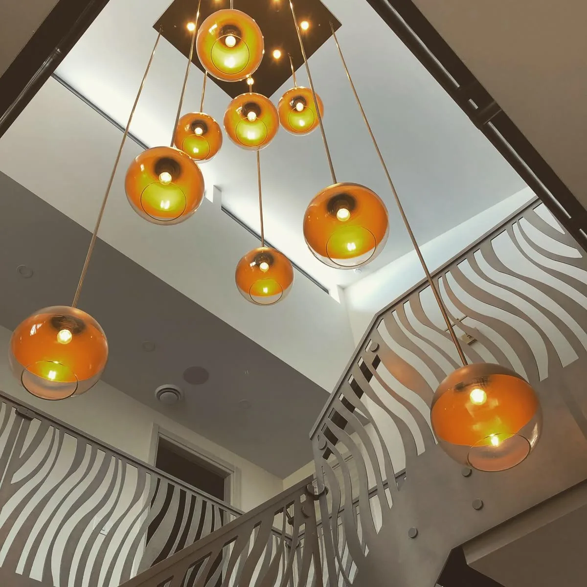 Globe pendant chandelier installed by Lighthouse Electrique in a two-storey stairwell